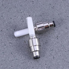 Metal and white T-shaped valve on a gray concrete surface